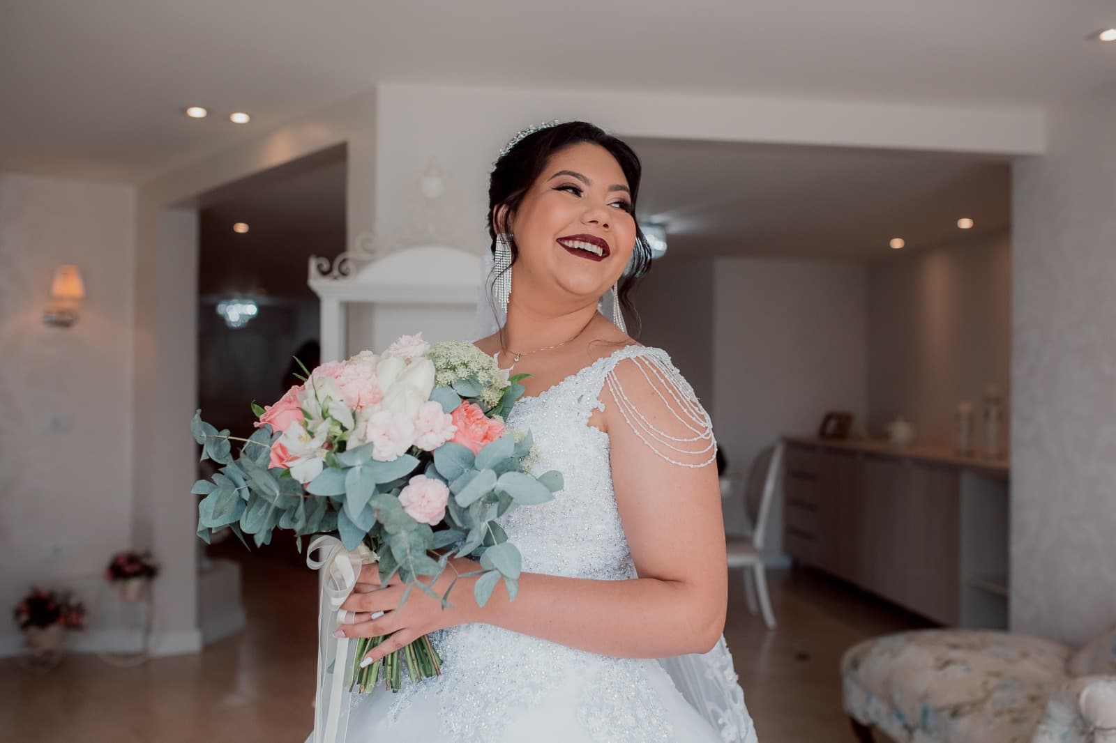 Convite de casamento e acessórios da noiva dispostos sobre a mesa do ateliê